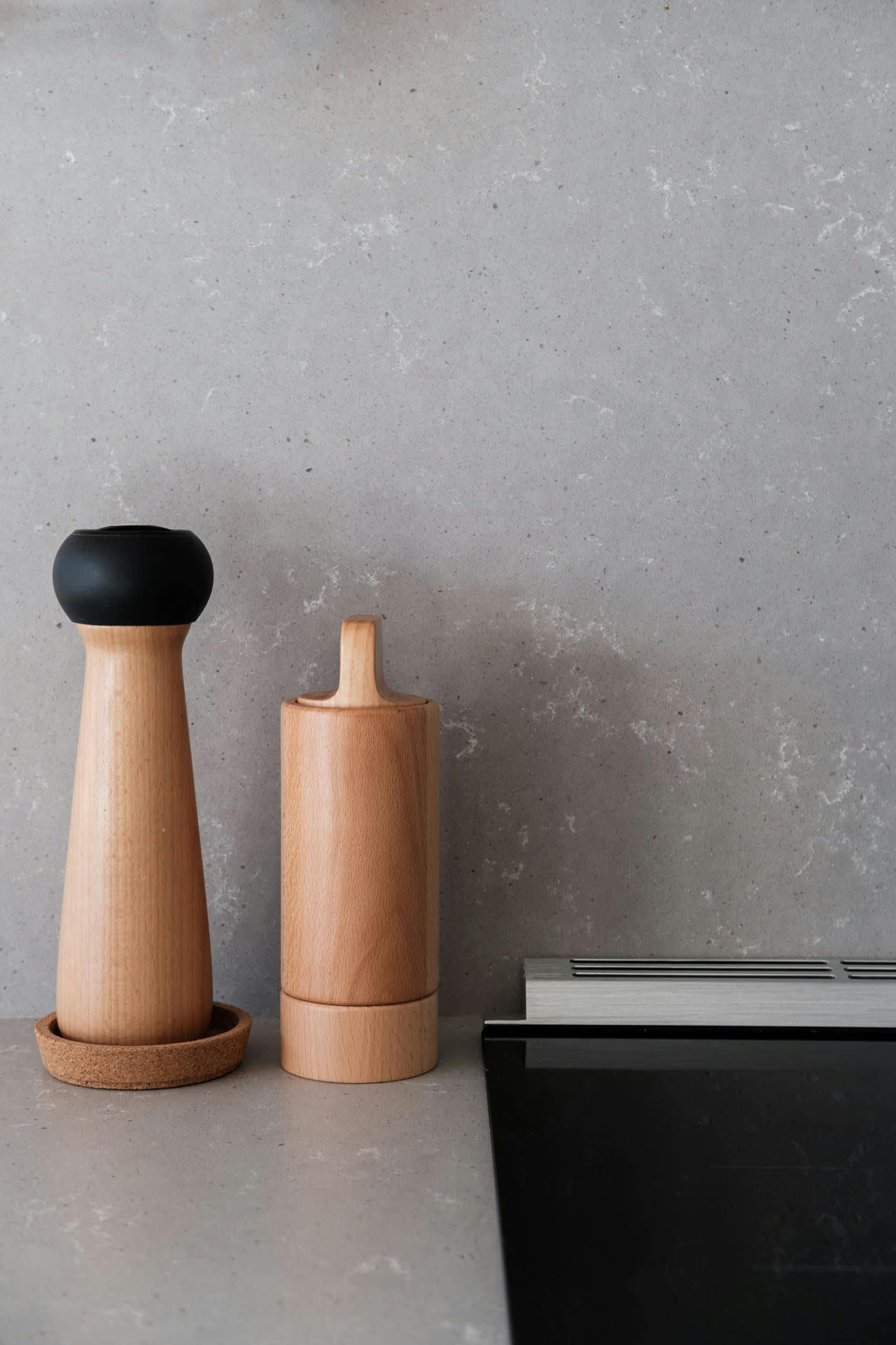 two wooden salt and pepper mill shakers on a countertop next to a toaster and toaster