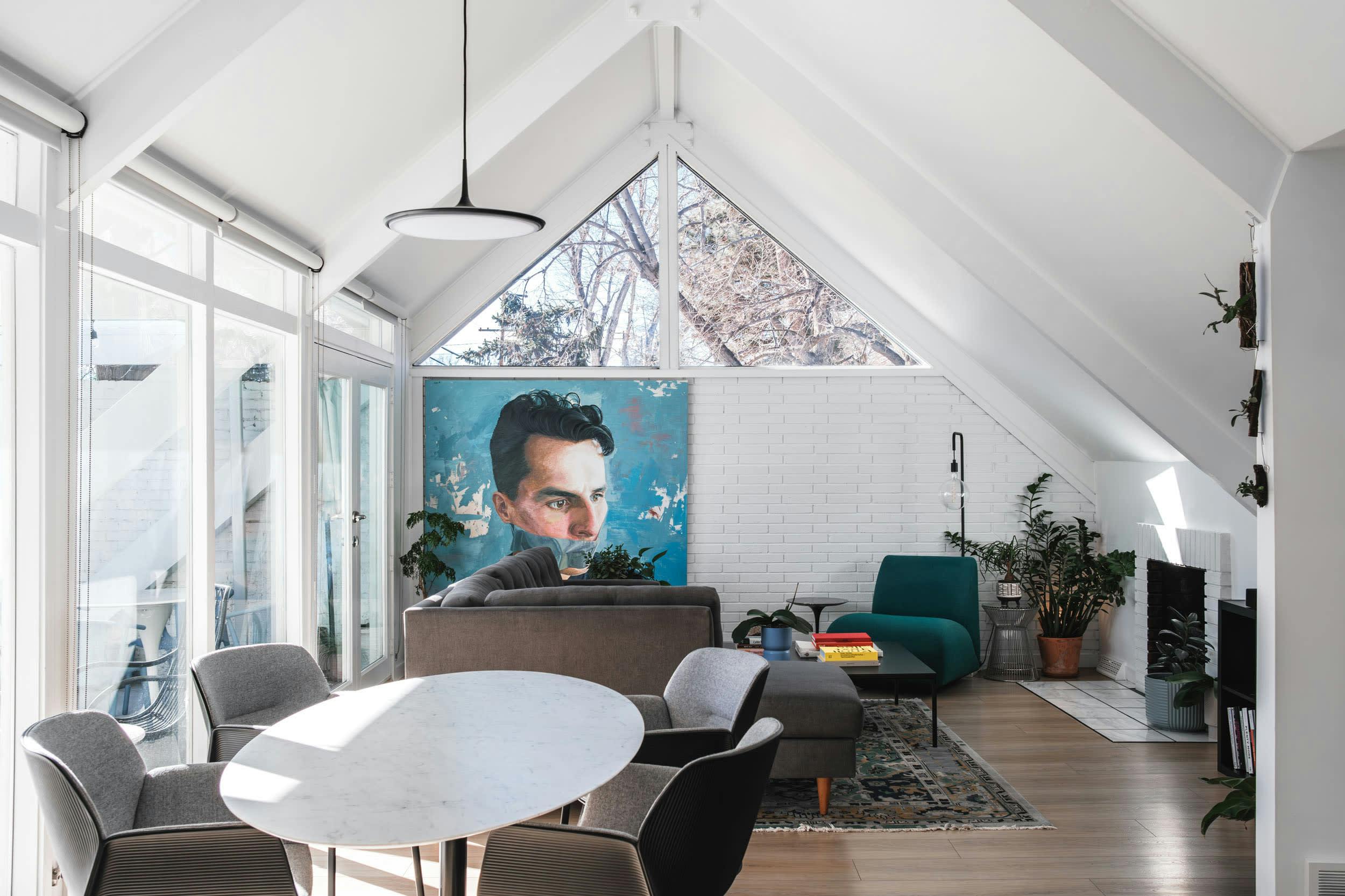 a living room with a large painting on the wall and a dining table in the middle of the room