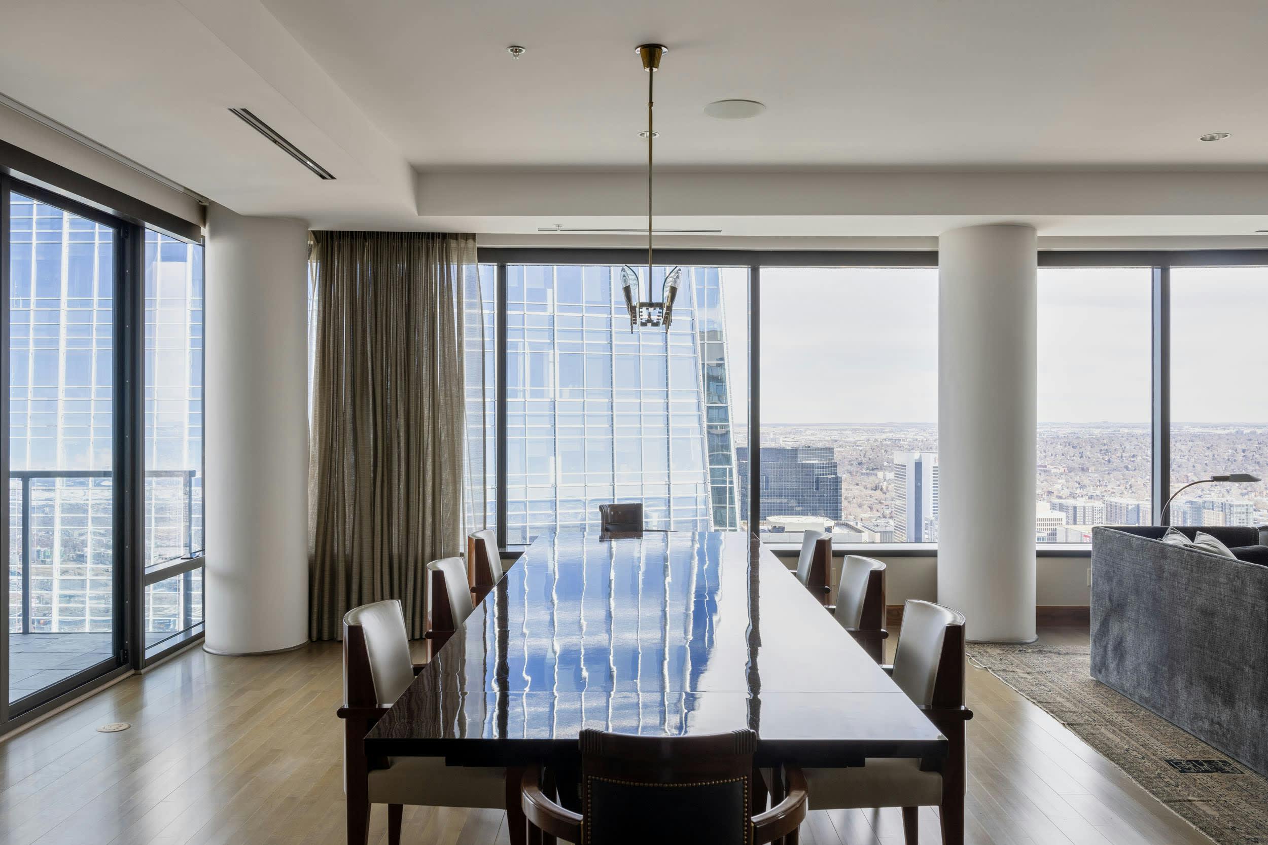 a dining room with a large table and a view of the city from the living room of a high rise building