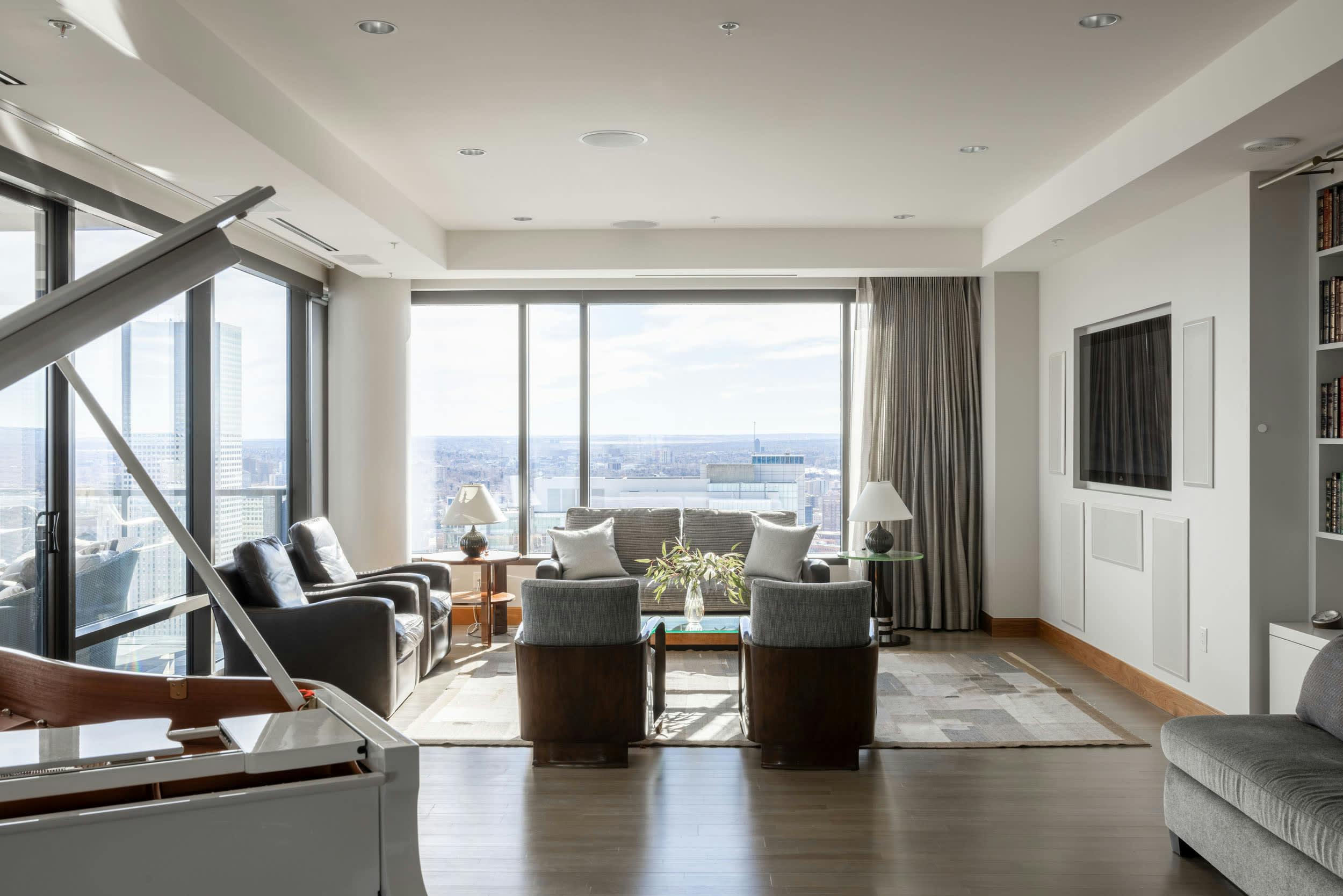 a living room filled with furniture and a large window overlooking a cityscape with a view of the city