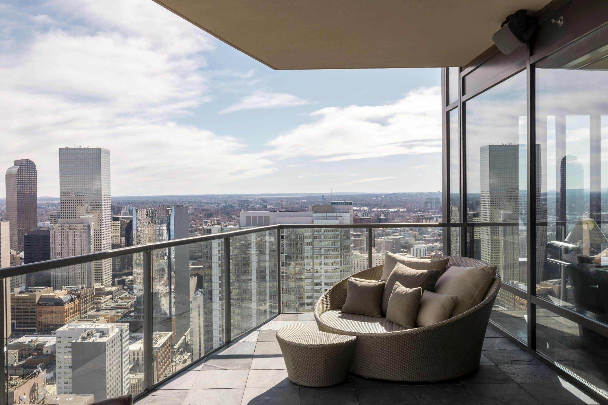 a balcony overlooking a city with a couch and a chair on the floor and a view of the city